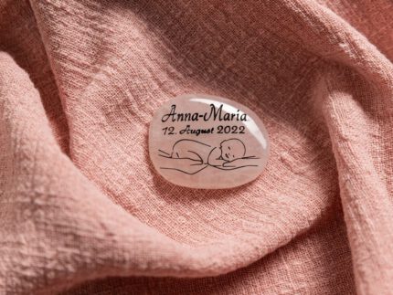 Stimmungsbild von einem ovalen, rosanem Erinnerungsstein mit Baby-Motiv.