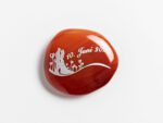 Produktbild von einem runden, glänzendem Taschenstein in rot mit einer weißen Gravur. Der Erinnerungsstein hat ein Hochzeits-Motiv eingraviert.