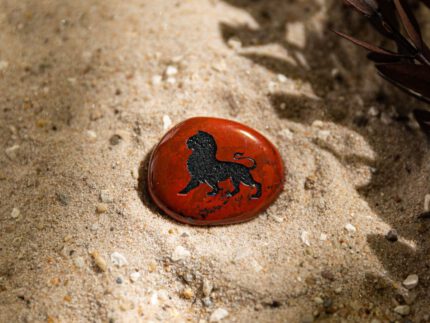 Stimmungsbild Handschmeichler mit Sternzeichen Löwe-Motiv liegt auf Sand