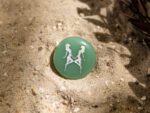 Taschenstein mit Zwilling-Motiv liegt auf Sand