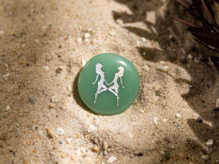 Taschenstein mit Zwilling-Motiv liegt auf Sand